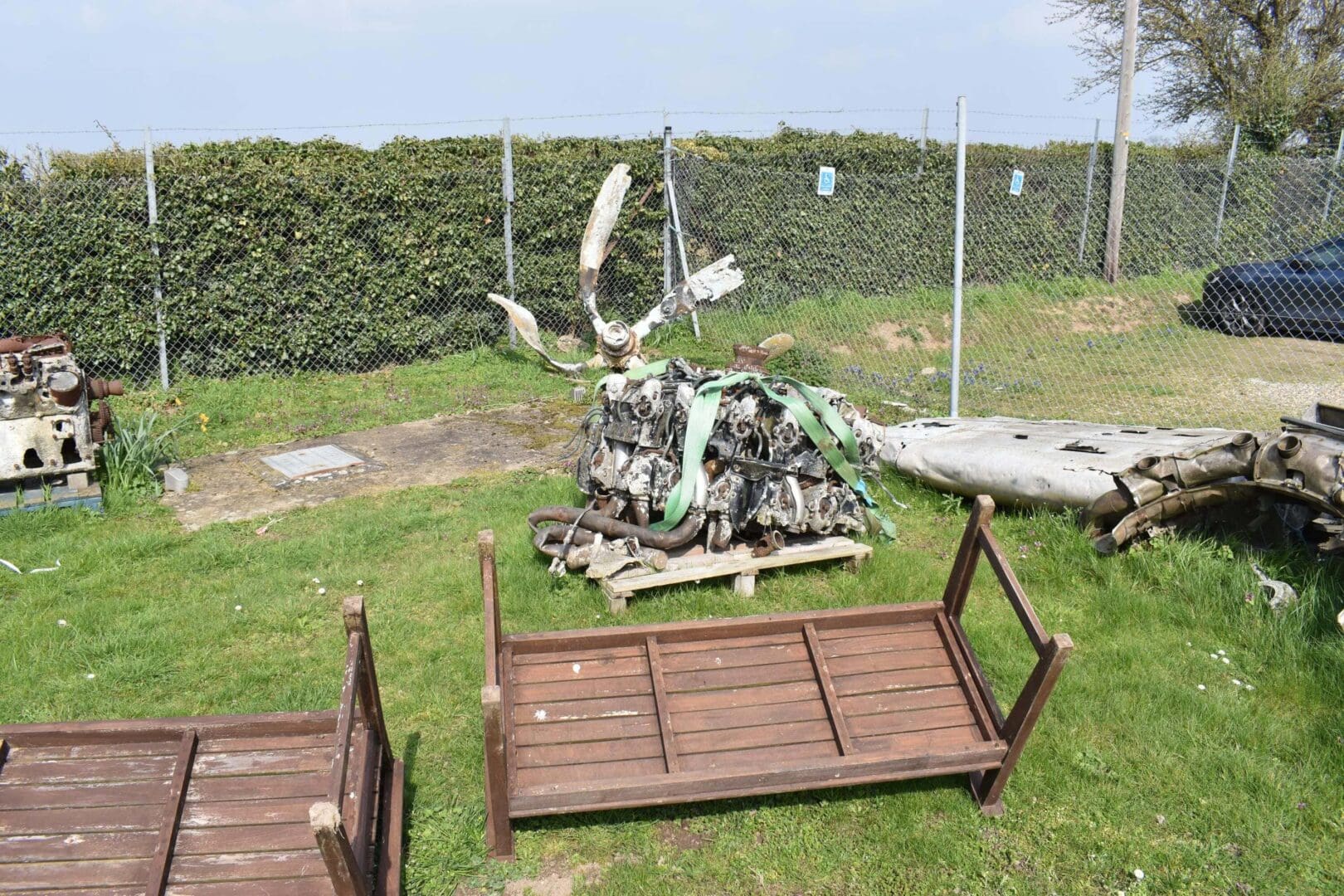 Old machinery and wooden crates on grass.