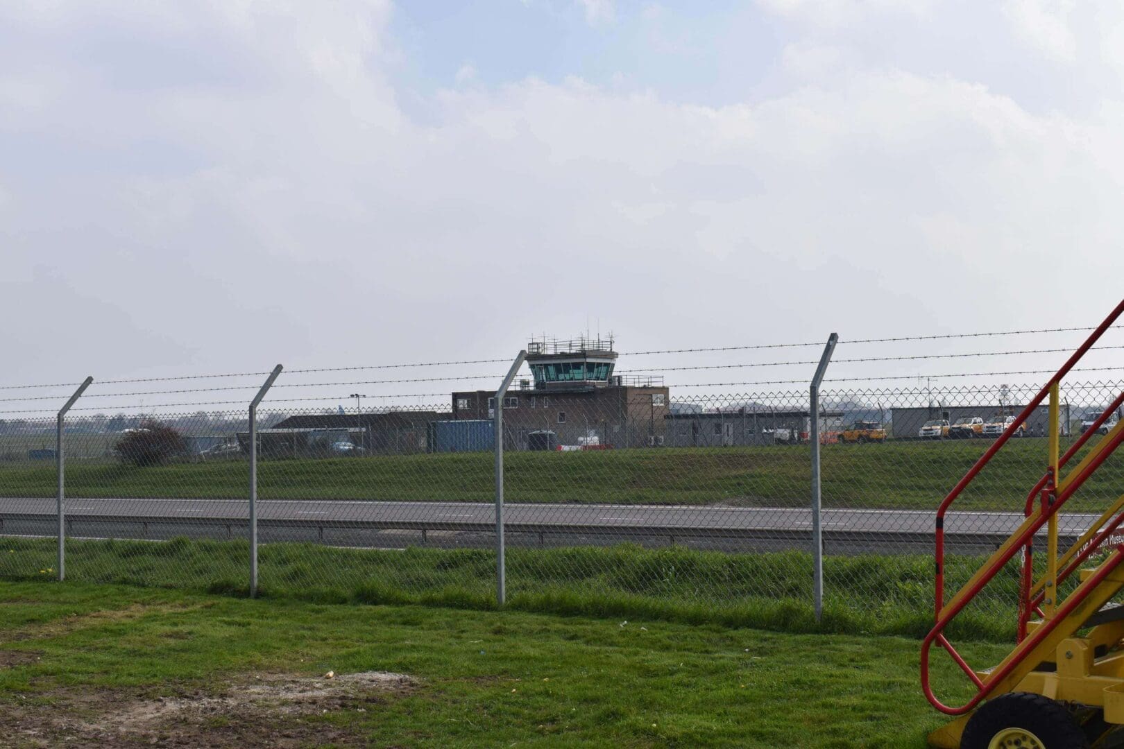 Airport control tower behind barbed wire fence.