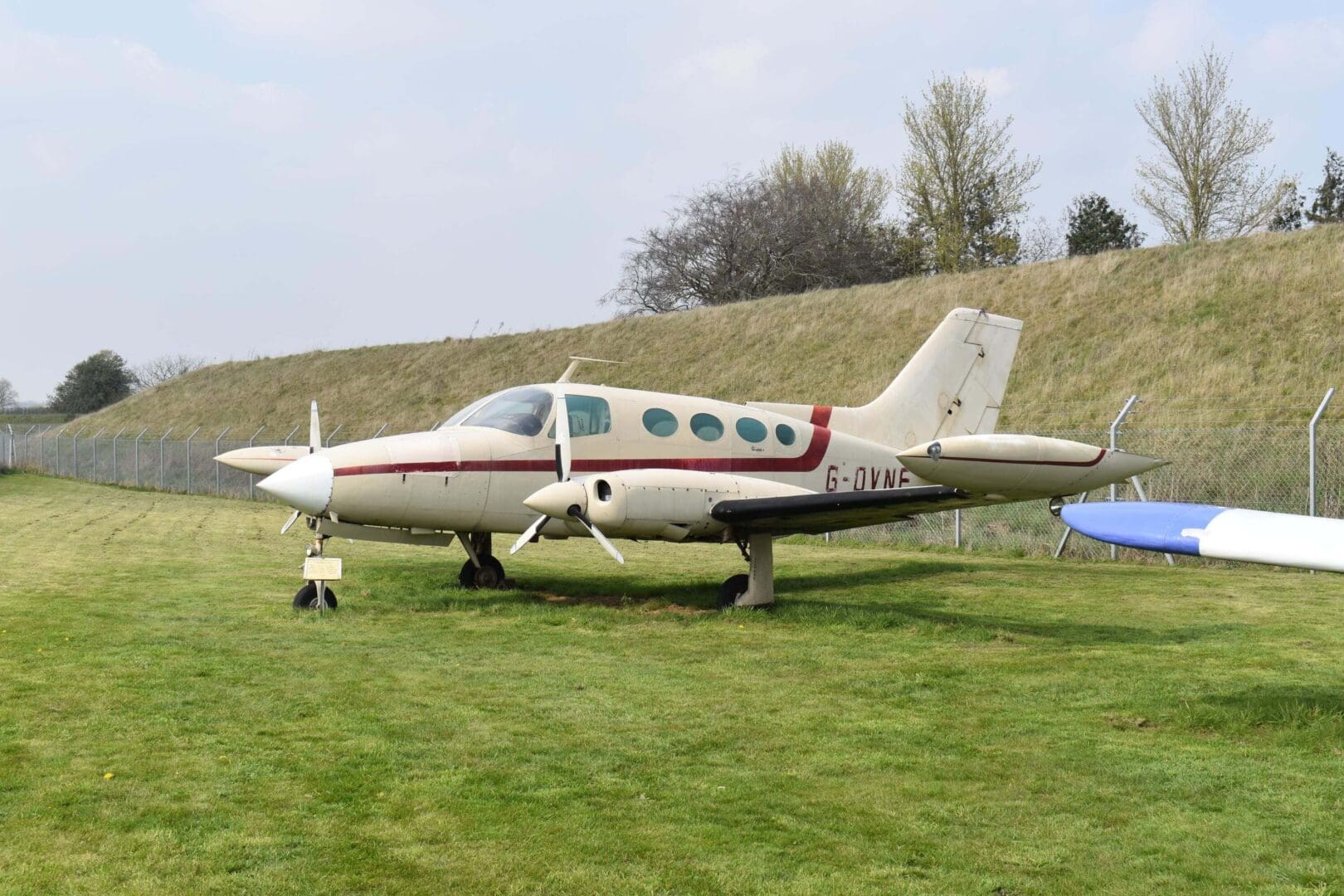 Small white aircraft parked on grassy field.