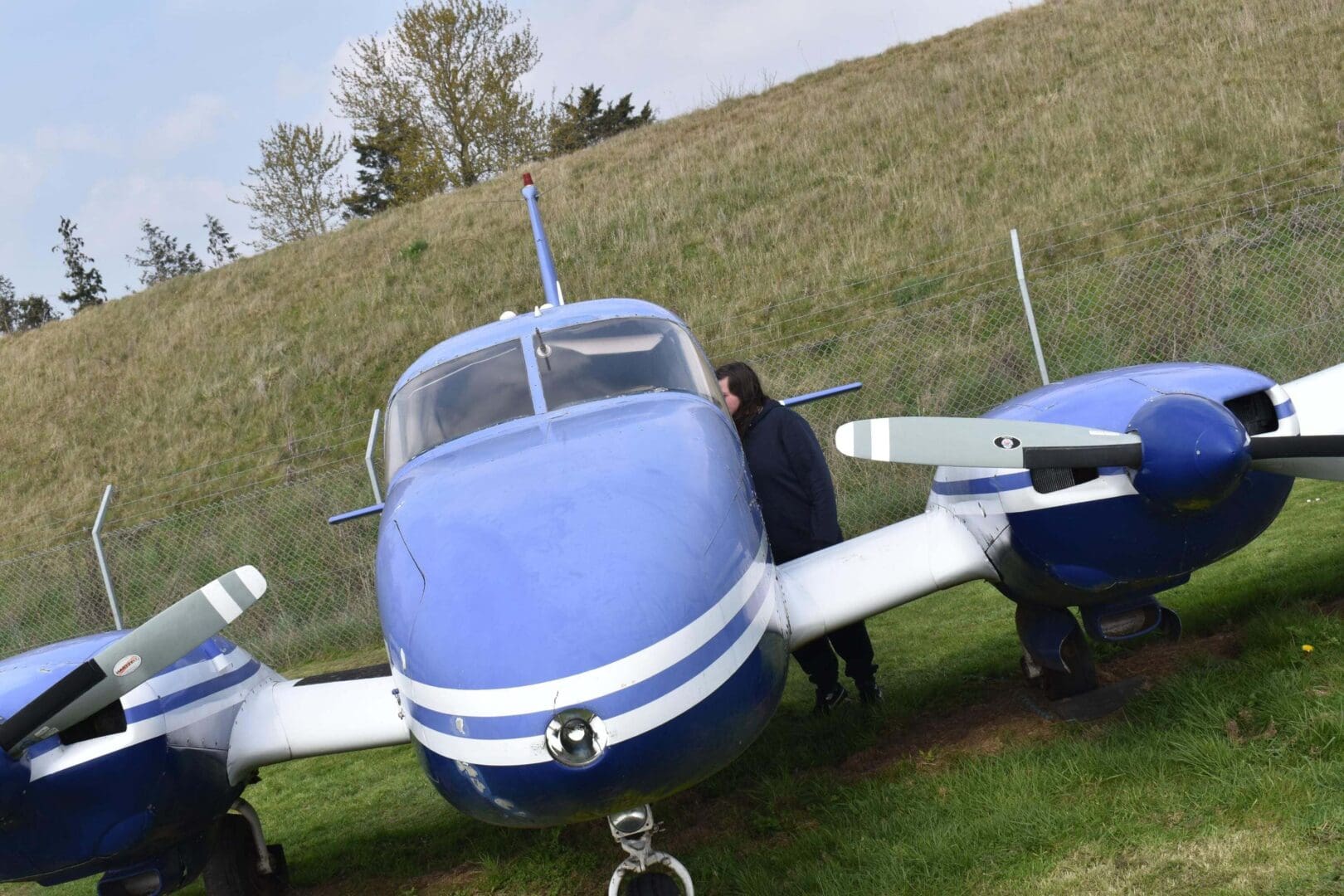 Blue twin-engine airplane on grassy field.