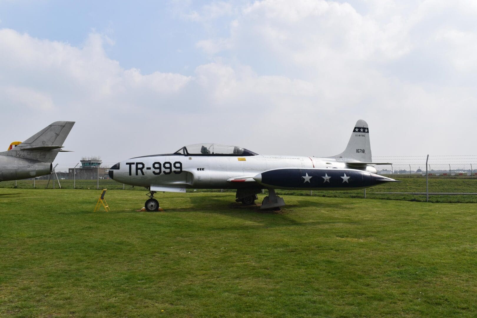Silver jet aircraft on grassy field display.