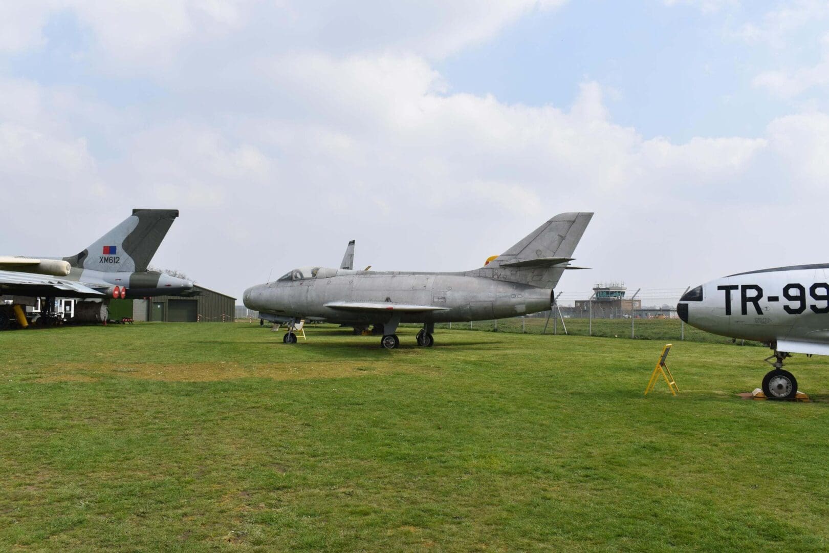 Three vintage airplanes displayed on grass field.