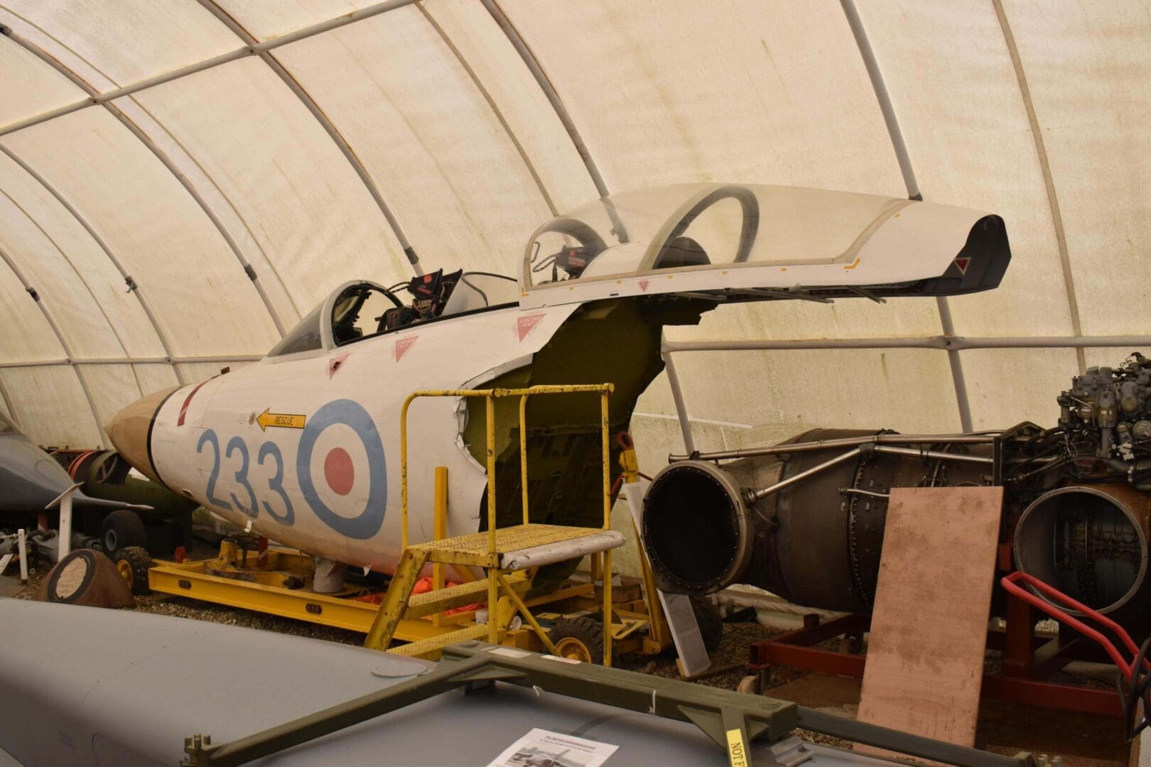 Vintage aircraft fuselage inside storage tent.