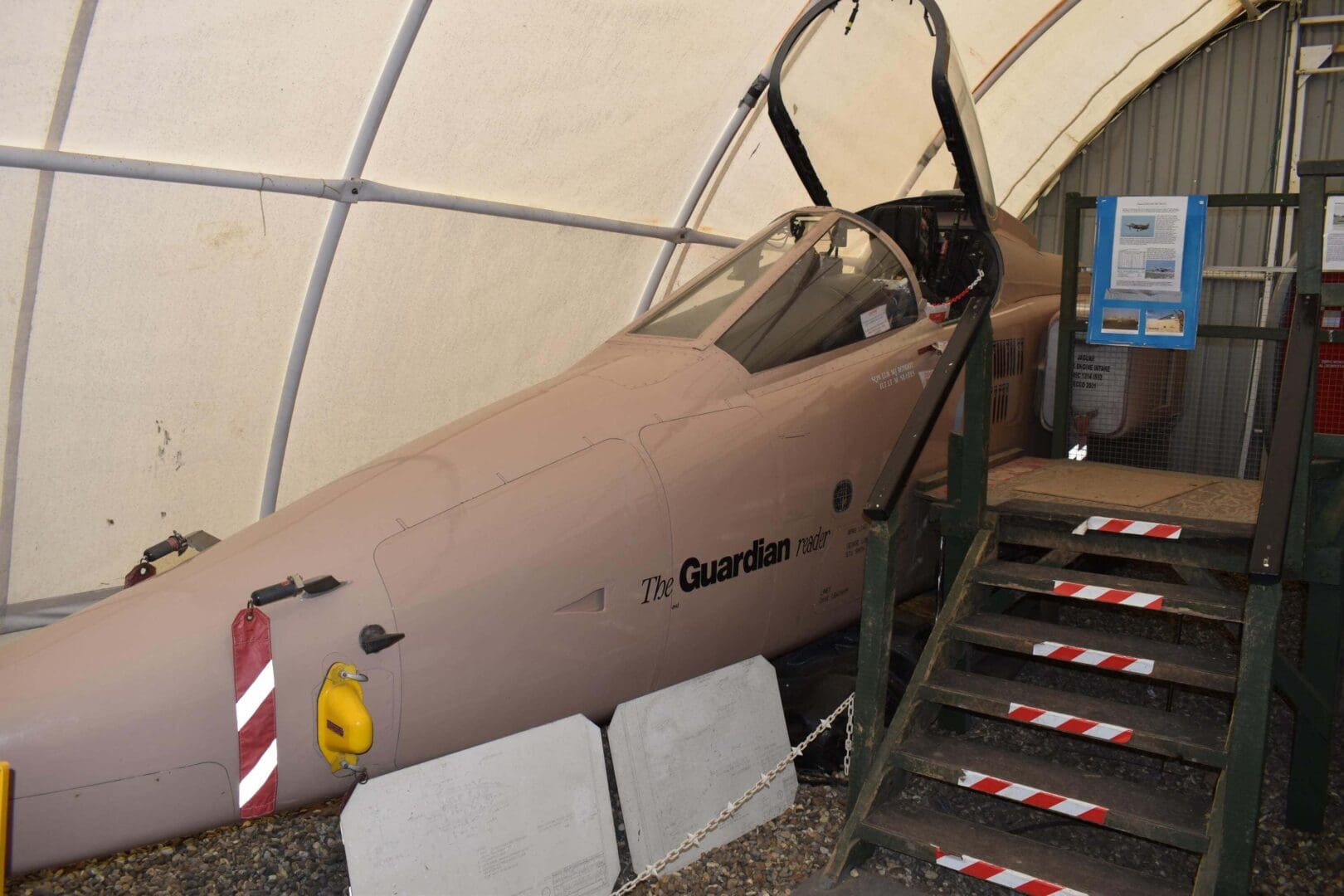 Military jet cockpit displayed in museum hangar.