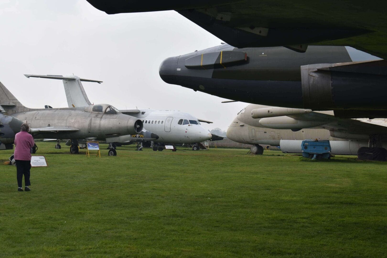 Person observing vintage aircraft on display outside.