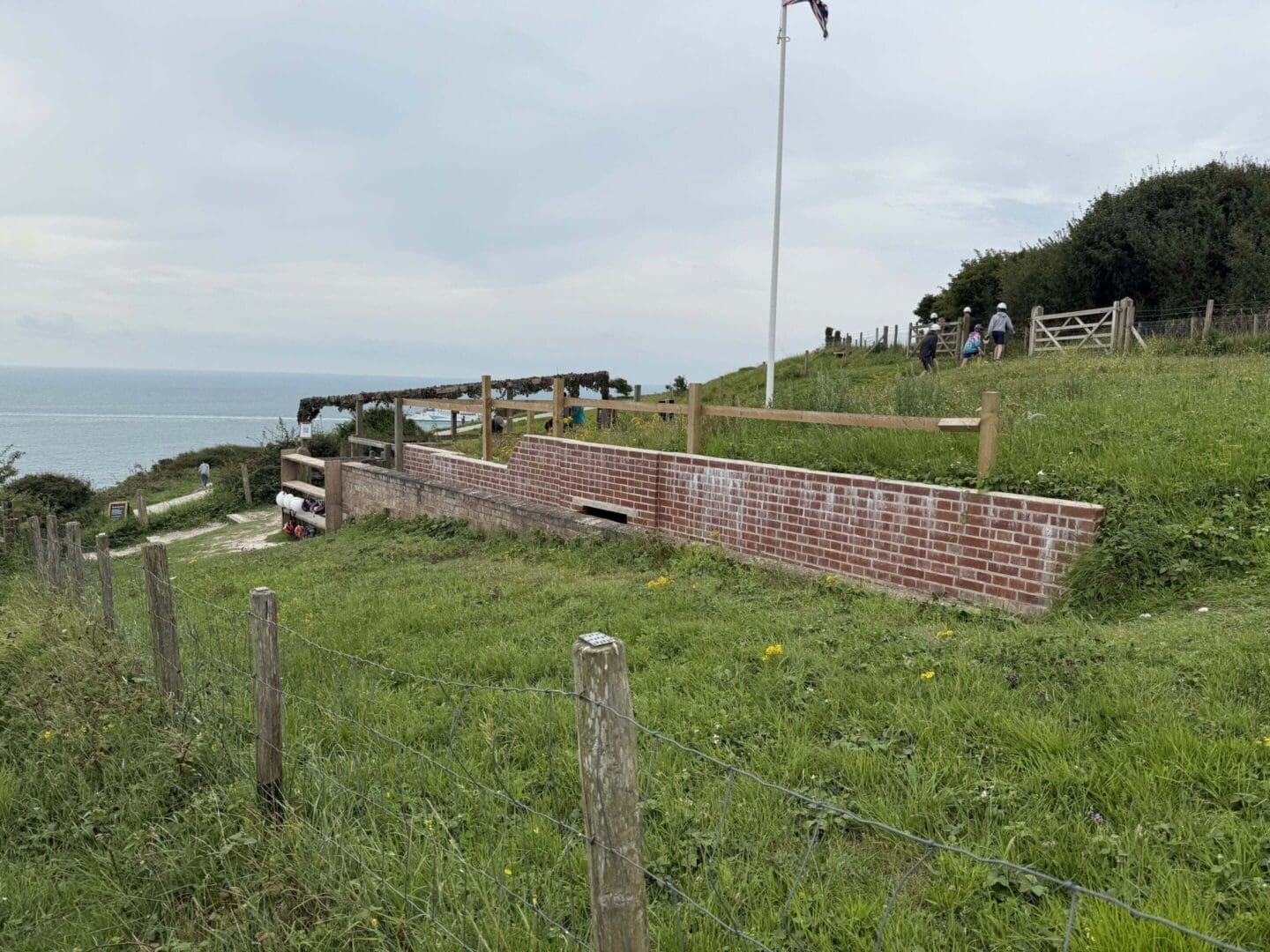 Coastal landscape with grassy hill and fence.