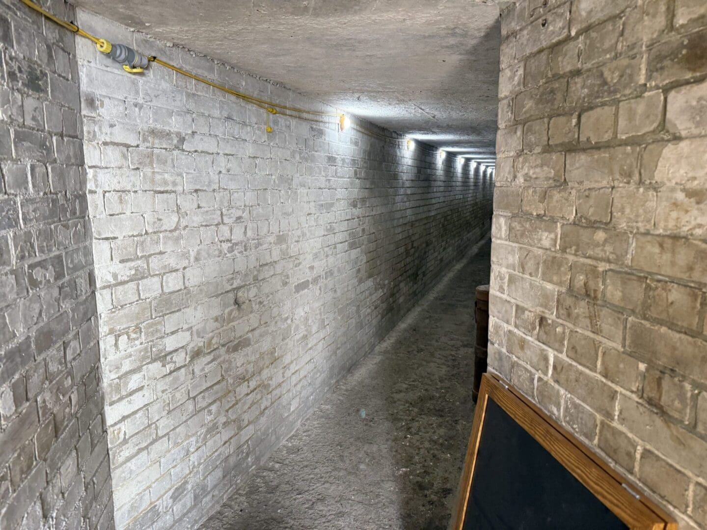 Dimly lit brick underground tunnel corridor.