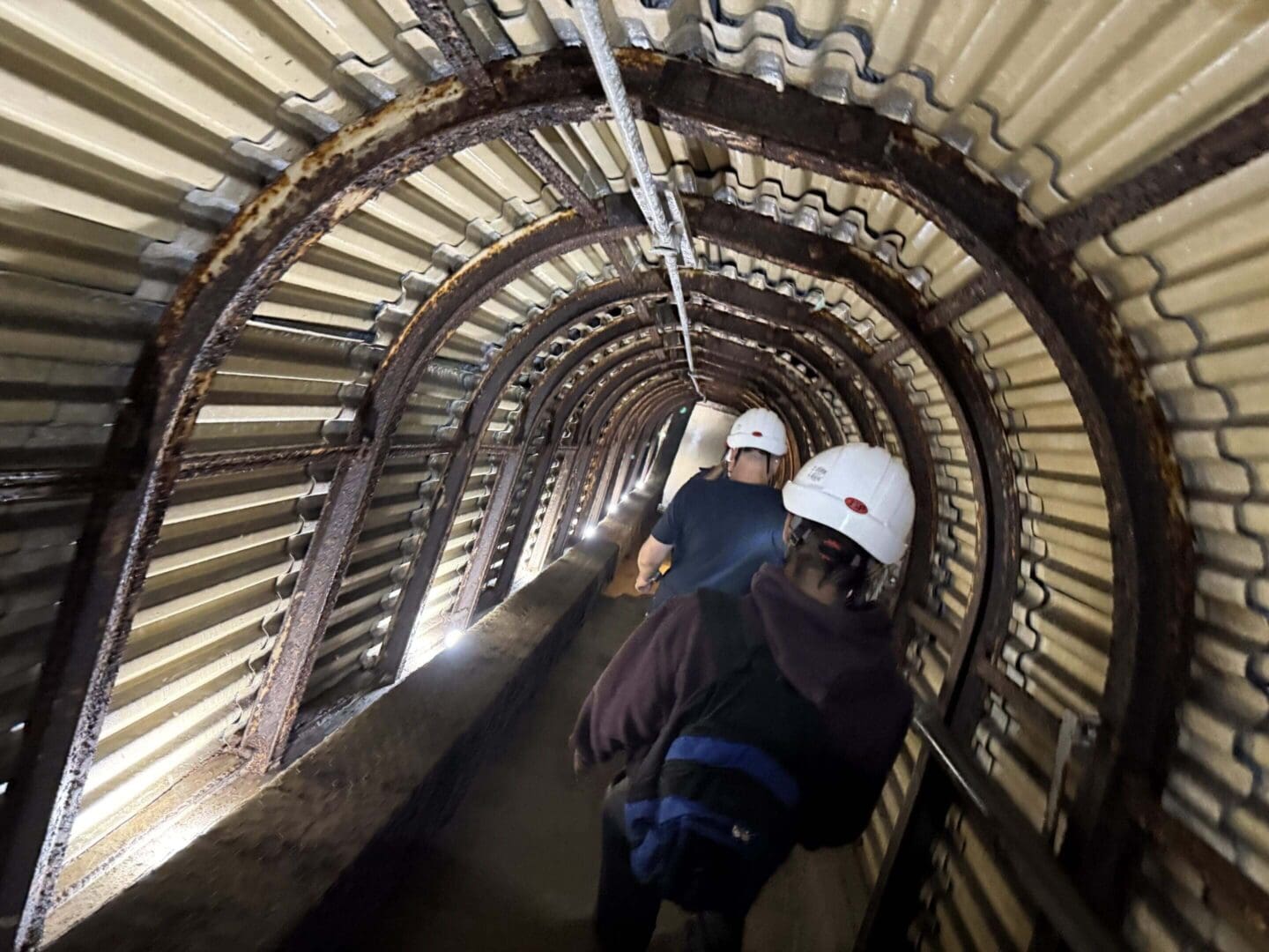 People walking in a metal tunnel.