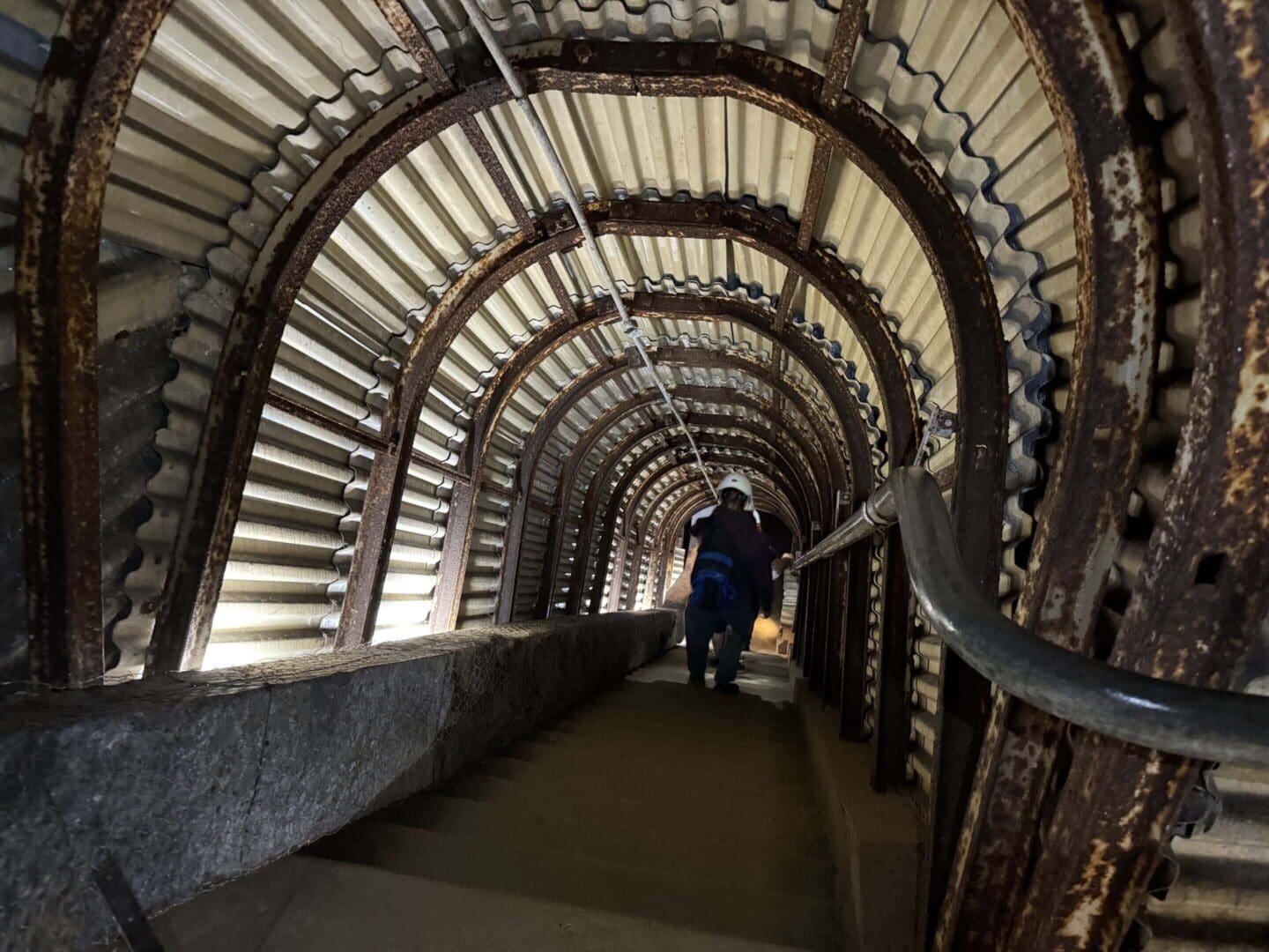 Person descending narrow, metal-lined staircase.