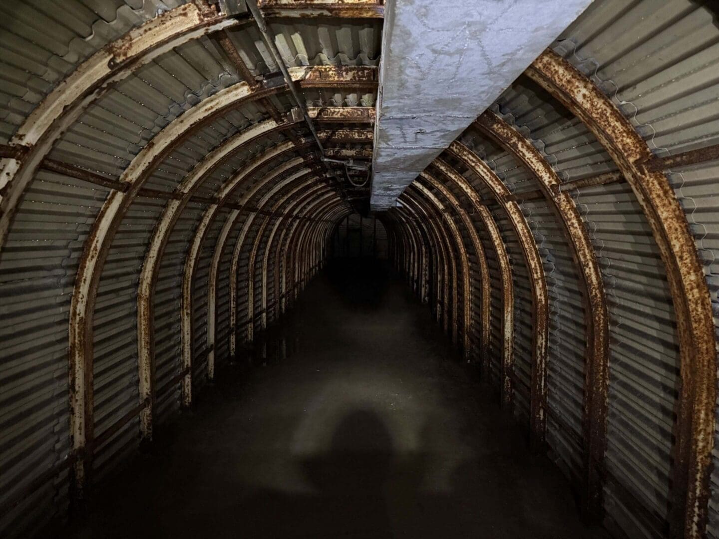 Rusty, dimly lit corrugated tunnel interior.