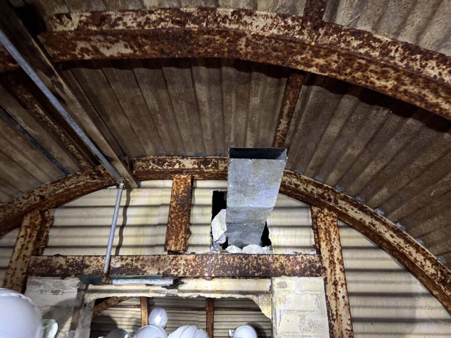 Rusty metal roof with exposed insulation hole.