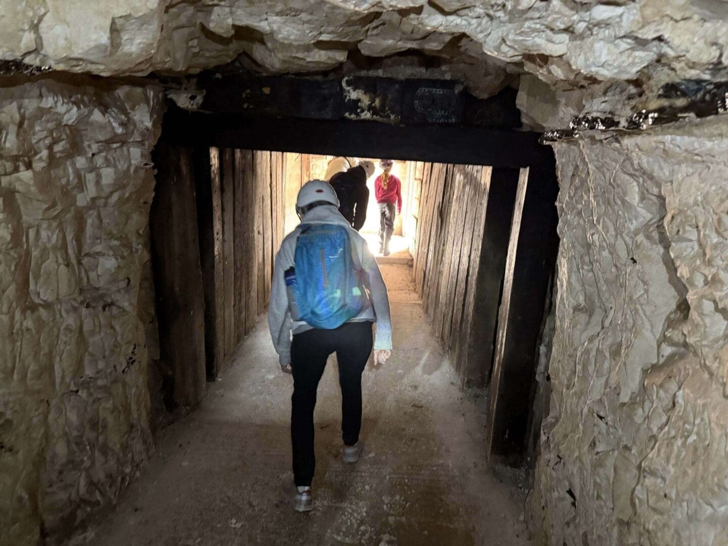 People exploring narrow underground mining tunnel.