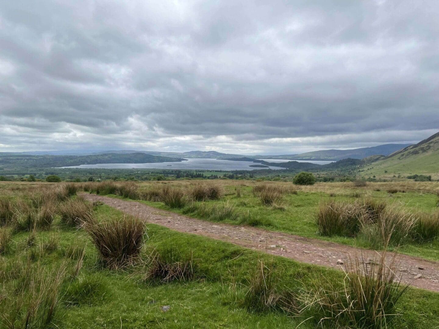 Cloudy landscape with grass and distant hills.